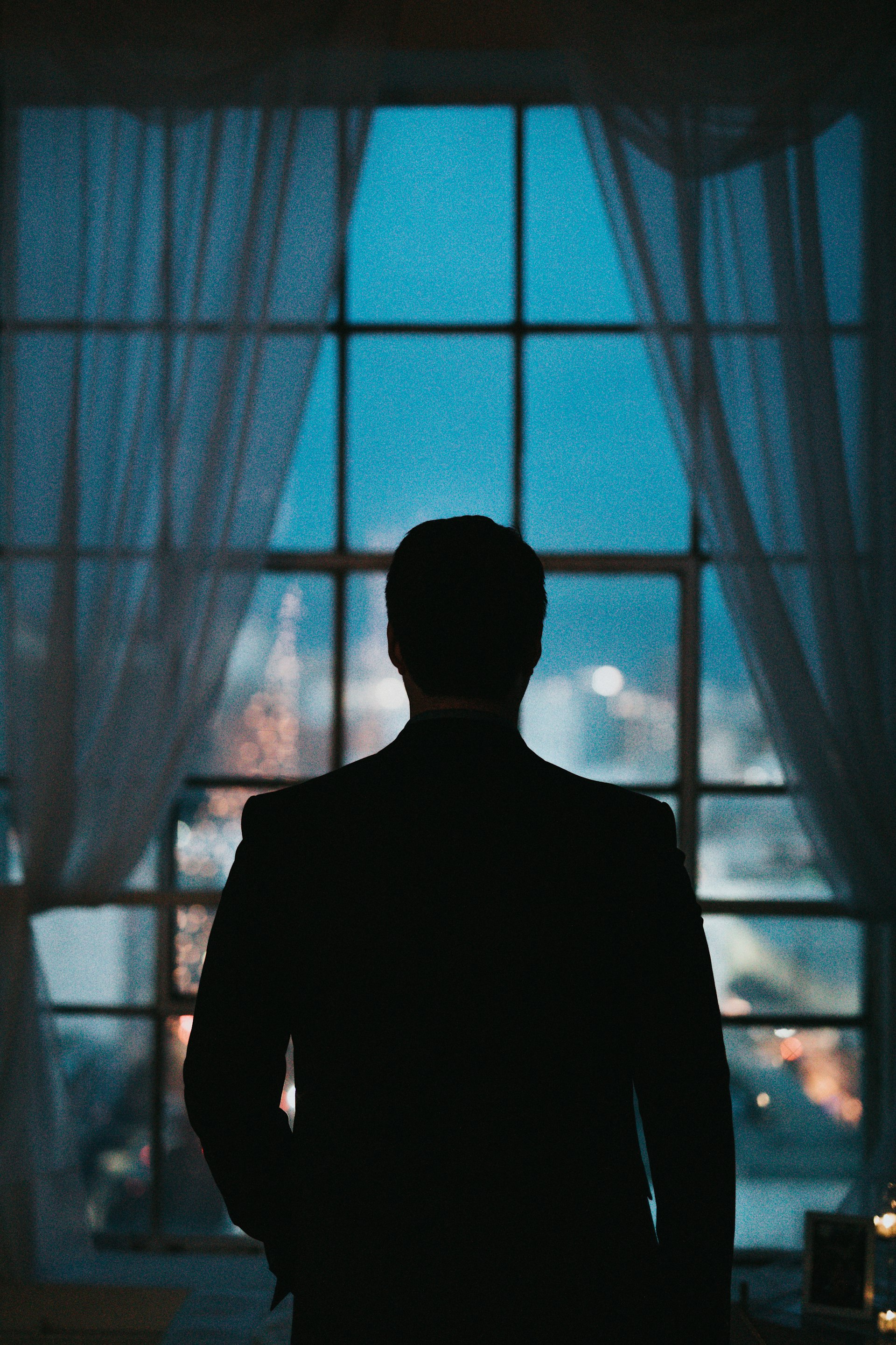 Silhouette eines Mannes im Anzug vor einem Fenster am Abend