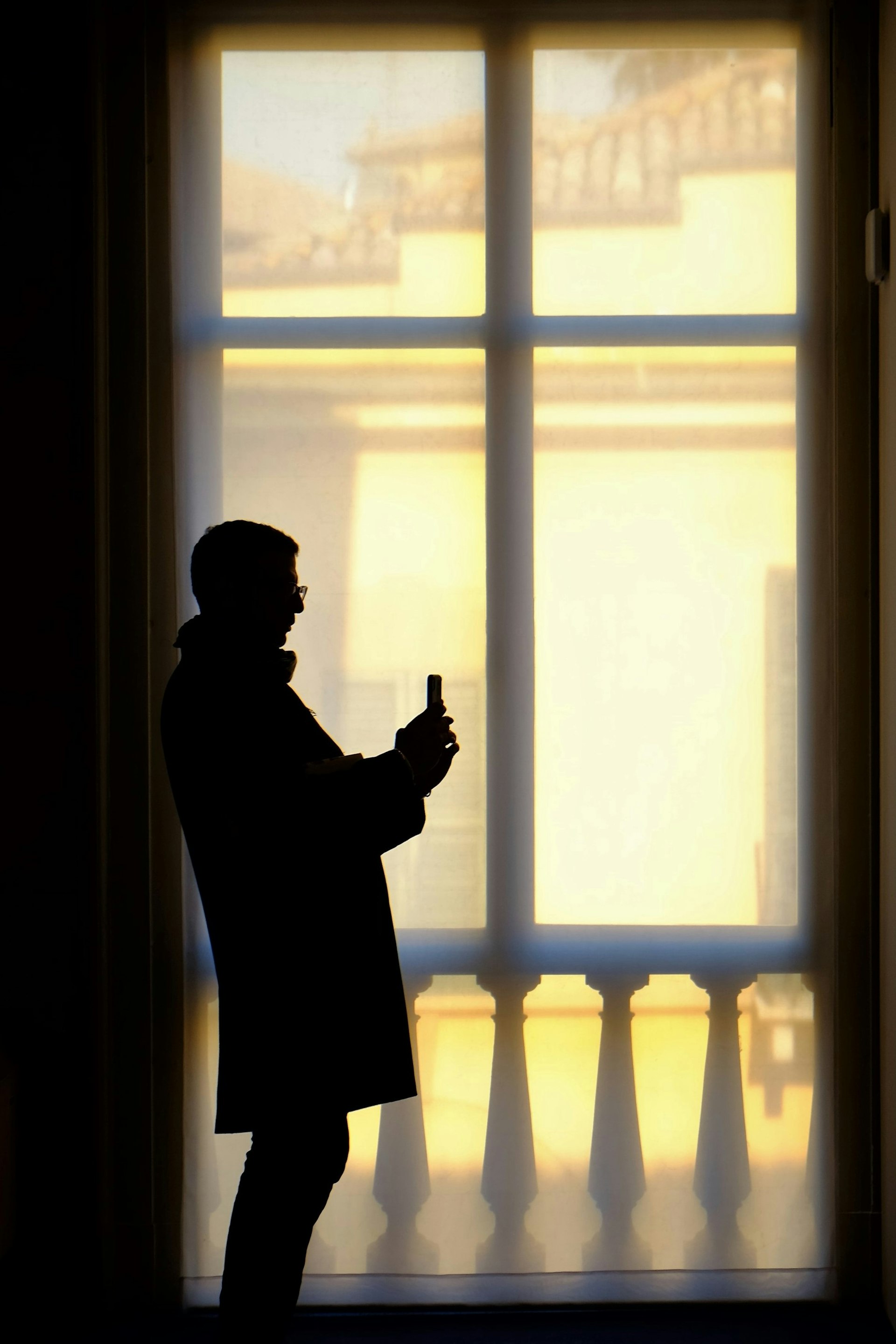 Silhouette eines Mannes im Mantel vor einem hellen Fenster